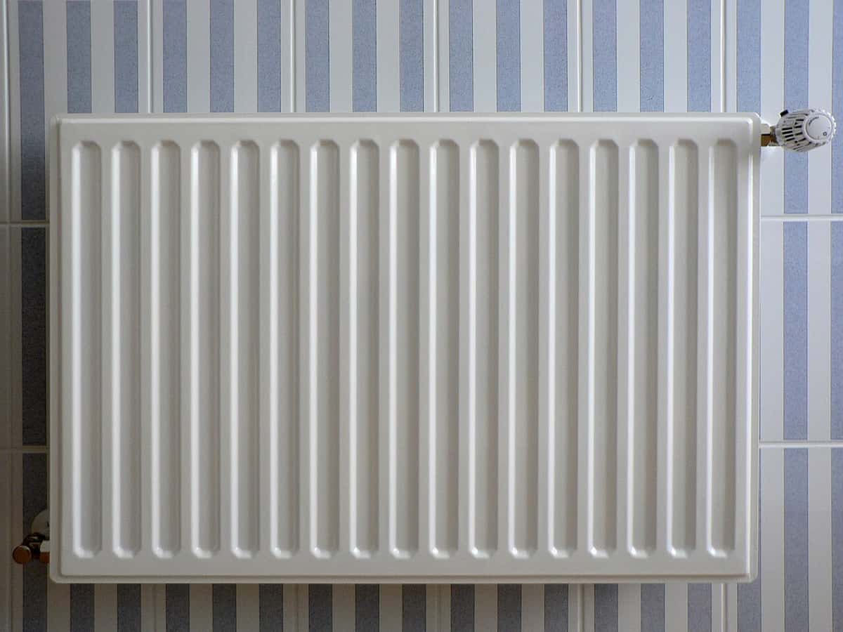 White panel radiator with a thermostatic valve on a wall
